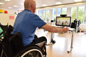 A man in a wheelchair lifting his arm to operate MindMotion GO