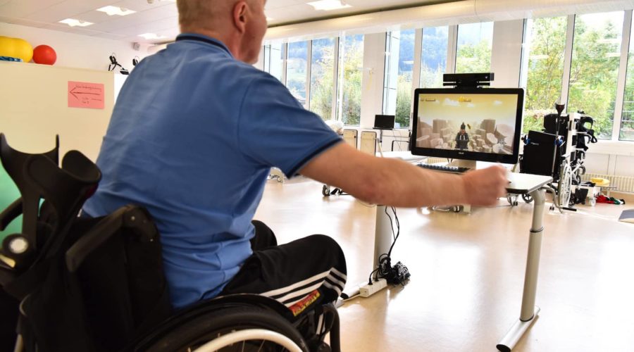 A man in a wheelchair lifting his arm to operate MindMotion GO